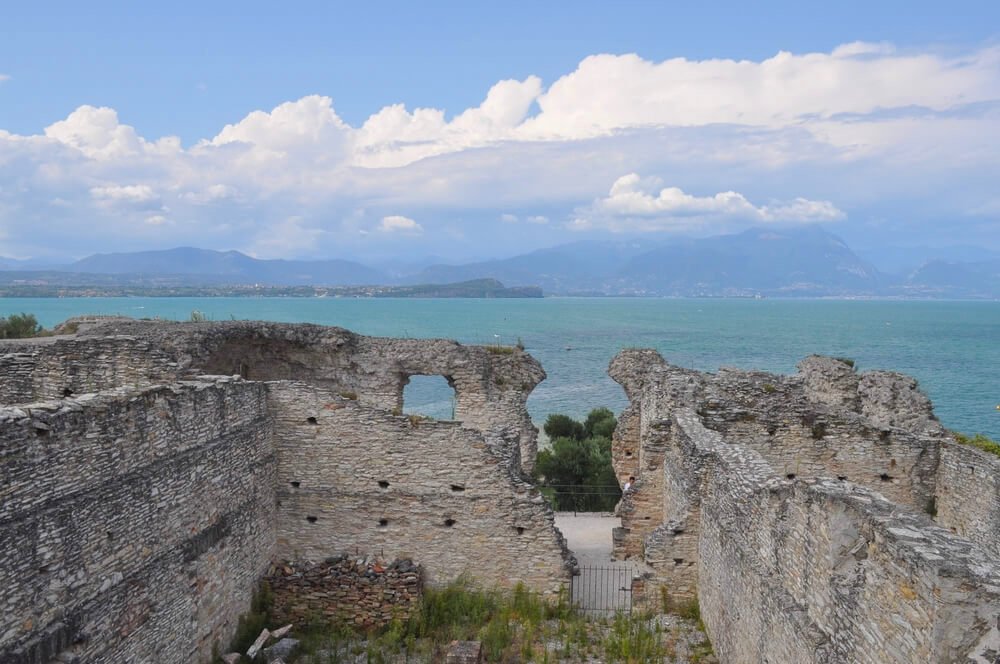 Grotte di Catullo (translation Grottoes of Catullus) in Sirmione, with turquoise-blue lake behind it, and ruins of stone wall villa from a roman era building