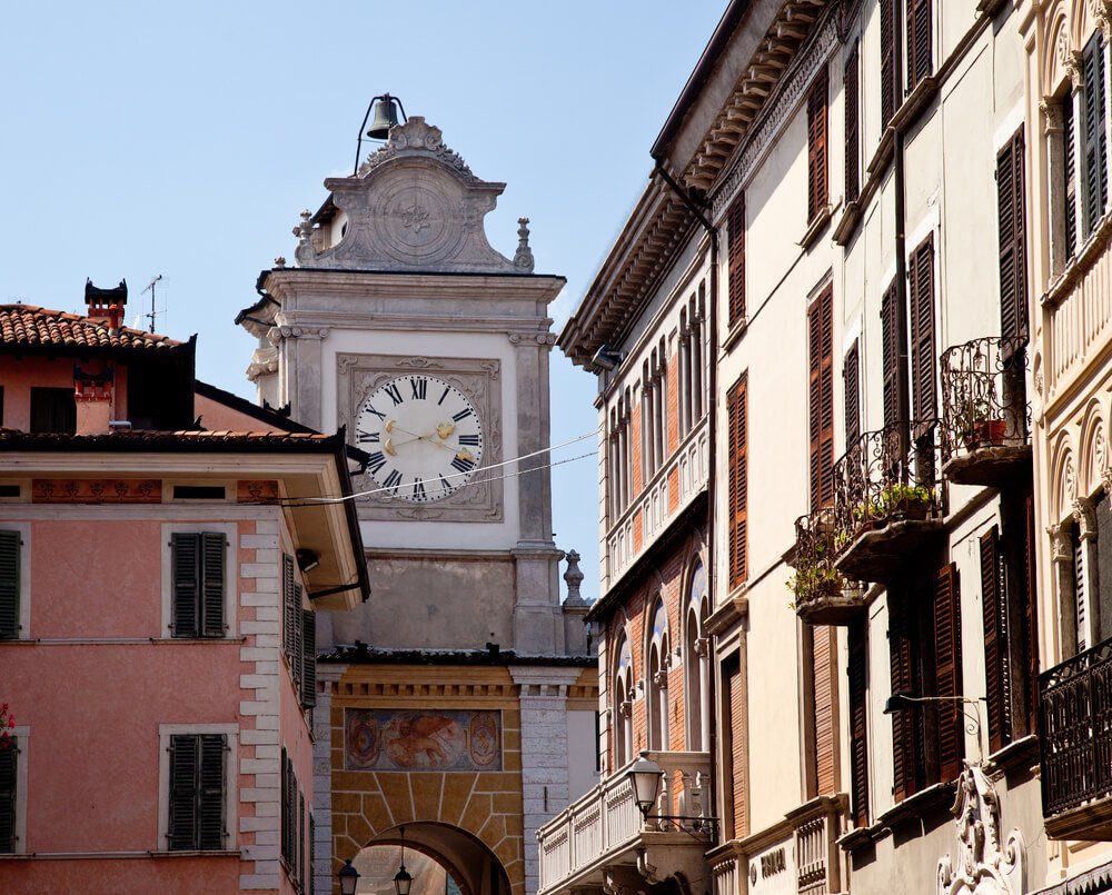 famous clocktower in salo's town center which has some detailing and balconies and other buildings int he center
