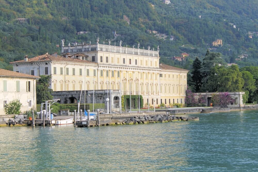 the giant pastel yellow building that is villa bettoni in gargnano, an old villa that is historic with gardens and lake views