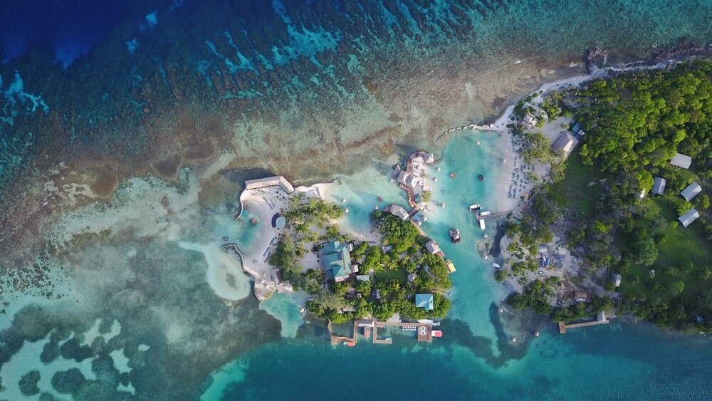 waters of little french key in roatan with reef and building development as seen from above (aerial shot from drone)