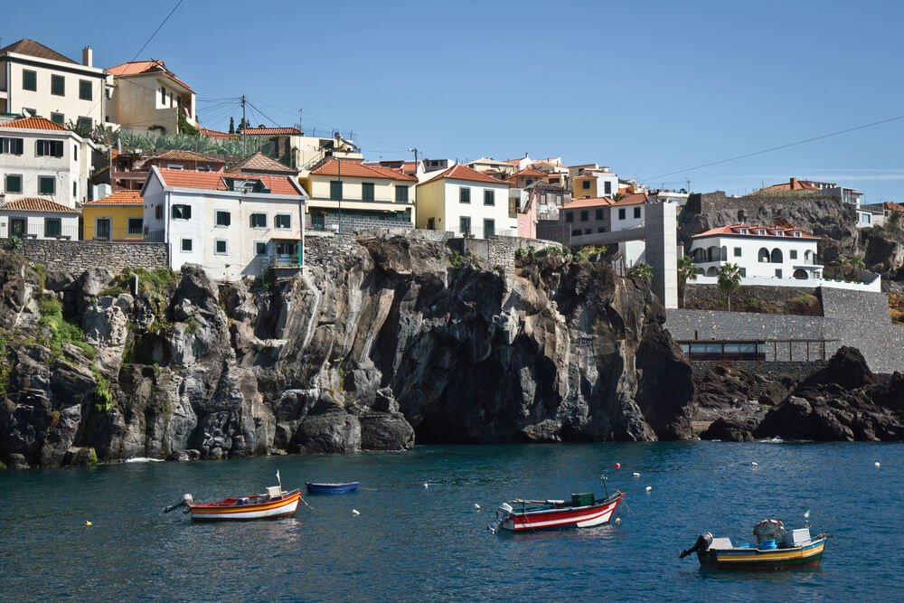 Small port in Madeira, Camara de Lobos, Portugal with fishing boats, cliffs, and villages on top of the cliff