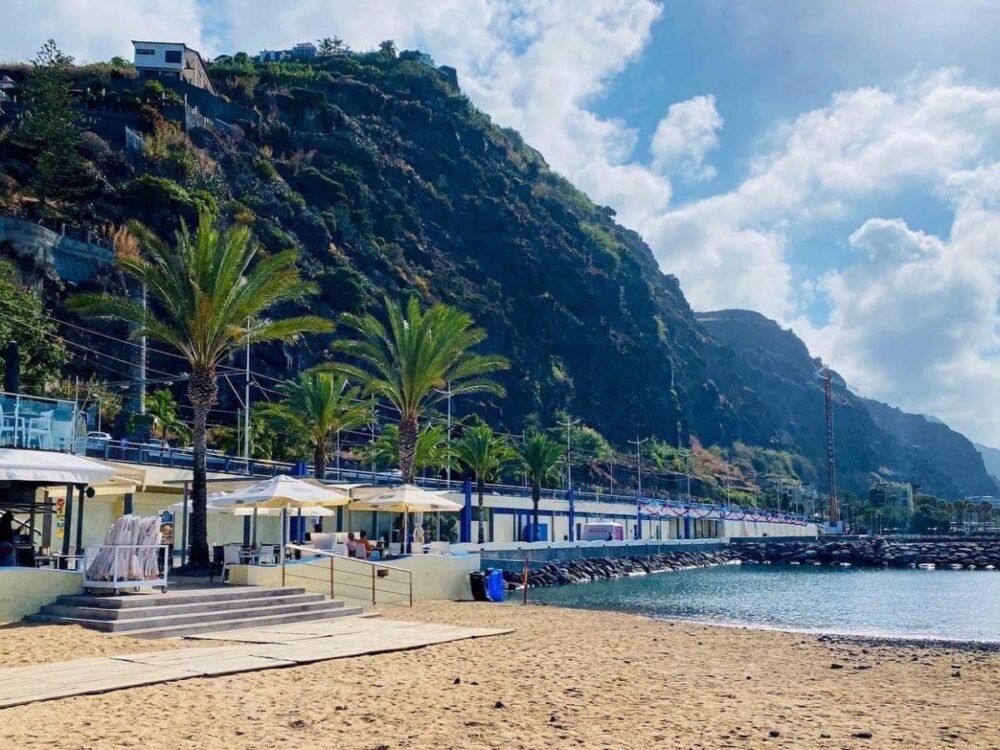 Sandy beach landscape of Madeira with rugged cliff landscape behind it