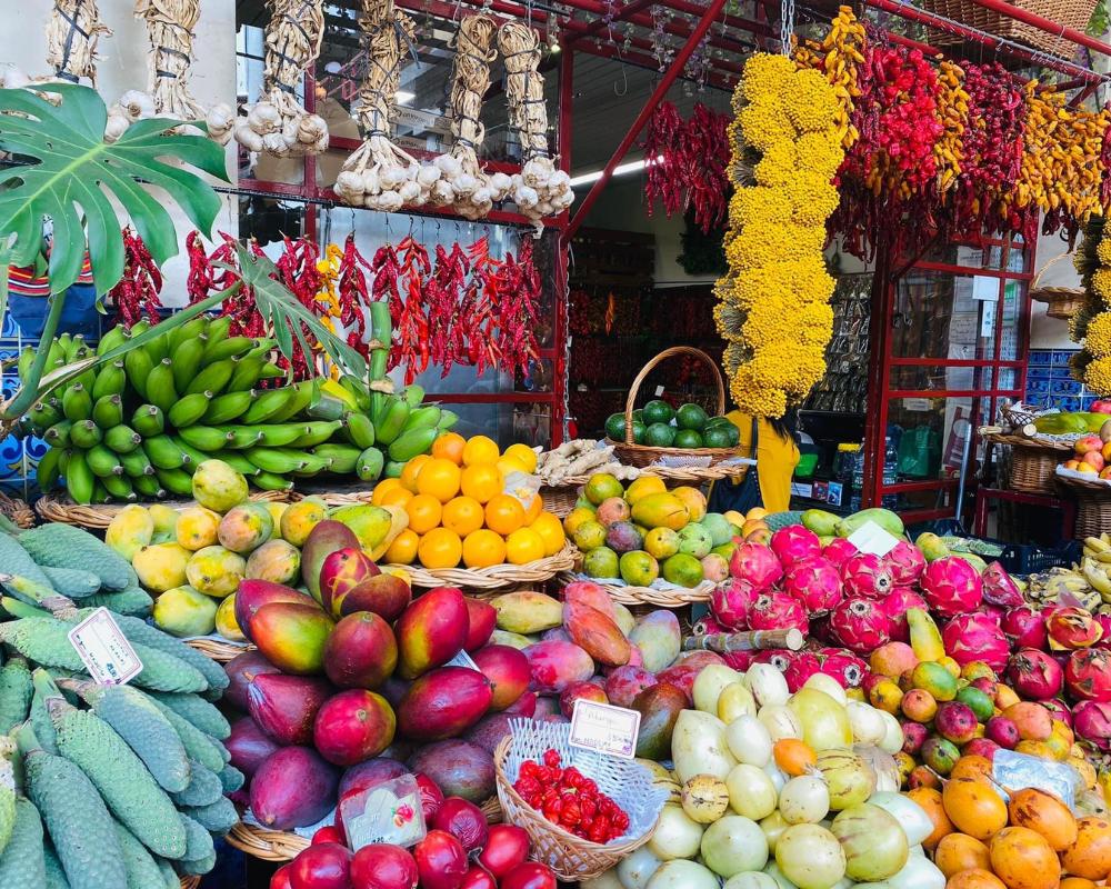 Fresh fruits and vegetables in the local market of Madeira, with colorful pink, orange, green and yellow fruits and vegetables.