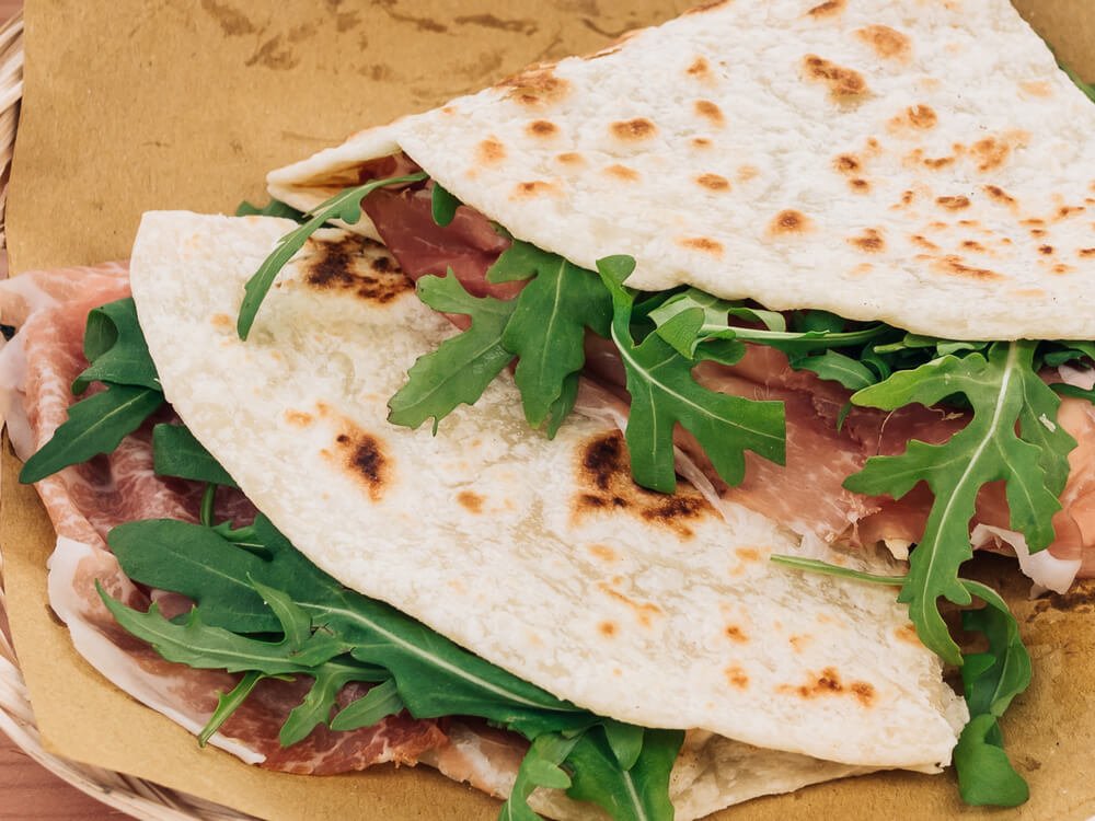 a piadina sandwich, a quick street food classic in italy with arugula and prosciutto