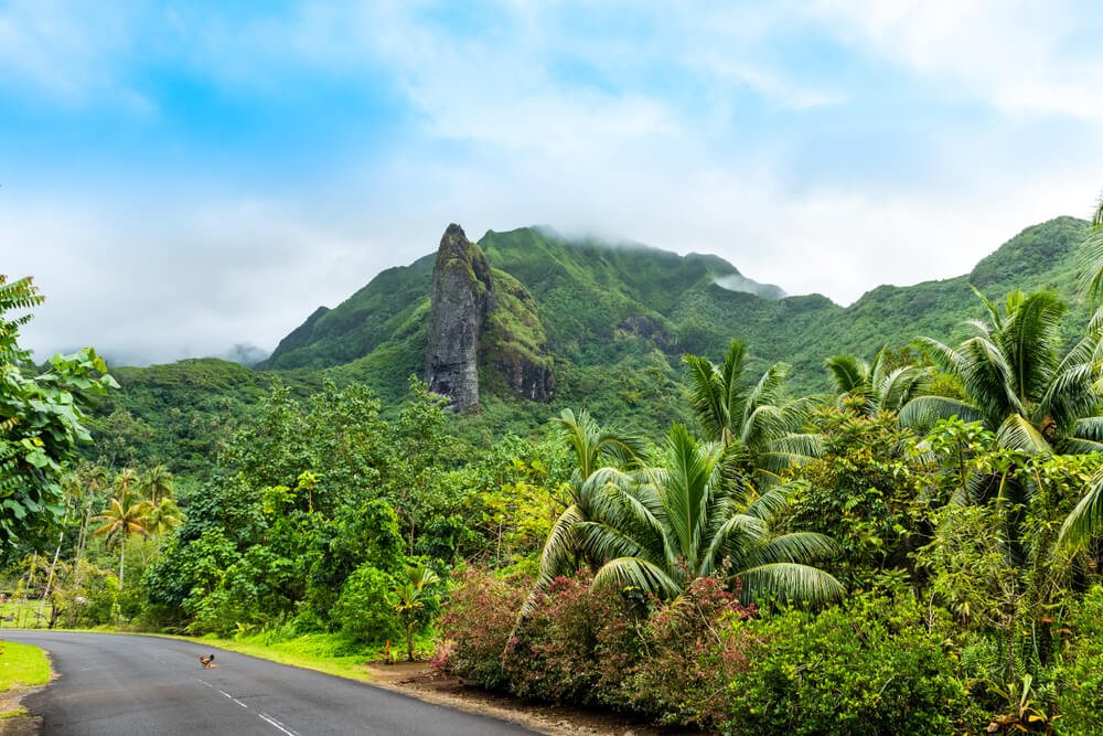 Mountain landscape of Raiatea island, French Polynesia, with road and lots of lush greenery around the island