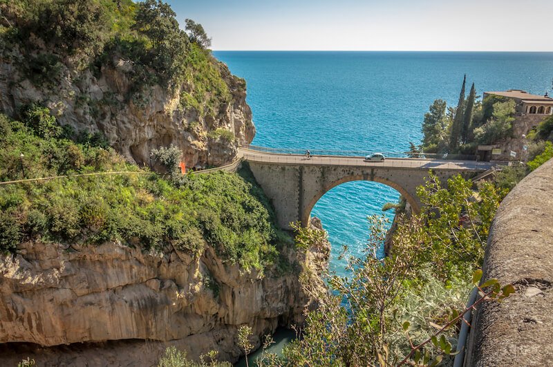 beautiful and high road in the amalfi coast over a fjord with blue sea behind before entering a tunnel