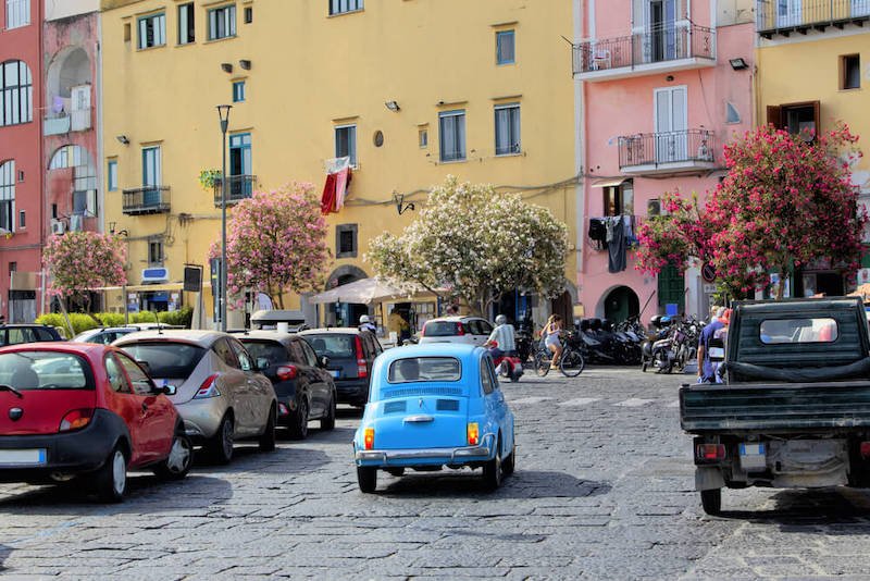 Italian little car fiat 500 blue in the streets of Procida Island Naples in Italy. The world famous Italian automobile brand in a cute sky blue color