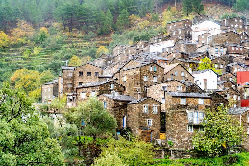 the charming, historic hillside village of piodao with mist on the mountains and terraced gardens and stone houses