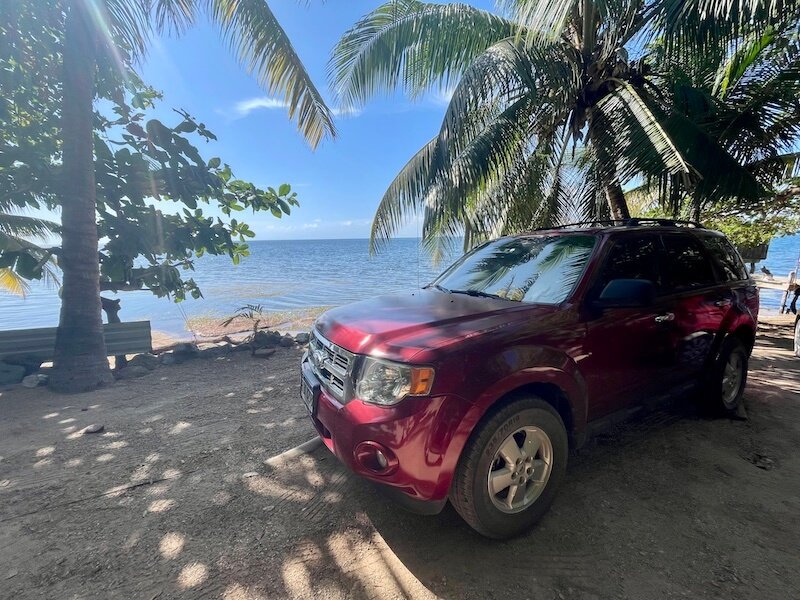 renting a red car in roatan against the blue background of the sea in camp bay at east end roatan