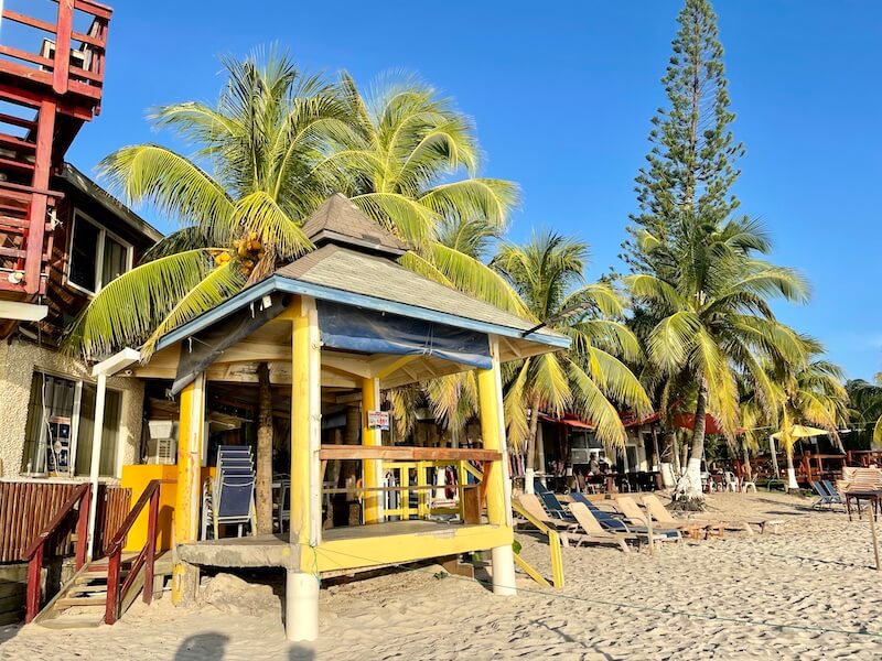 roatan honduras beach club view with yellow building palm trees and beach chairs