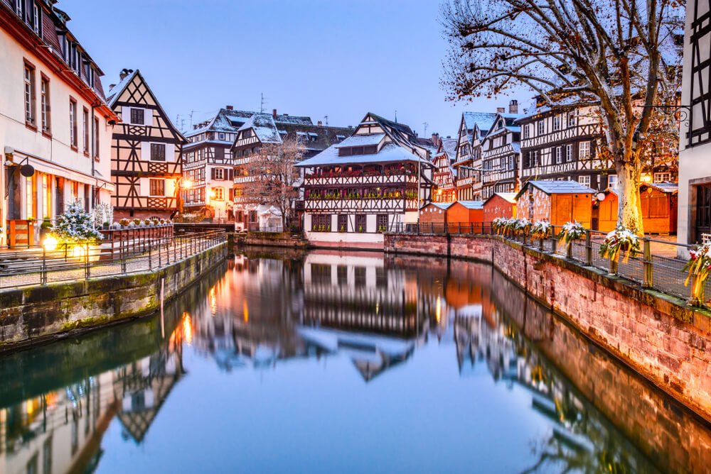 canal in strasbourg with mistletoe tastles on the canal with half-timbered houses with christmas market stalls