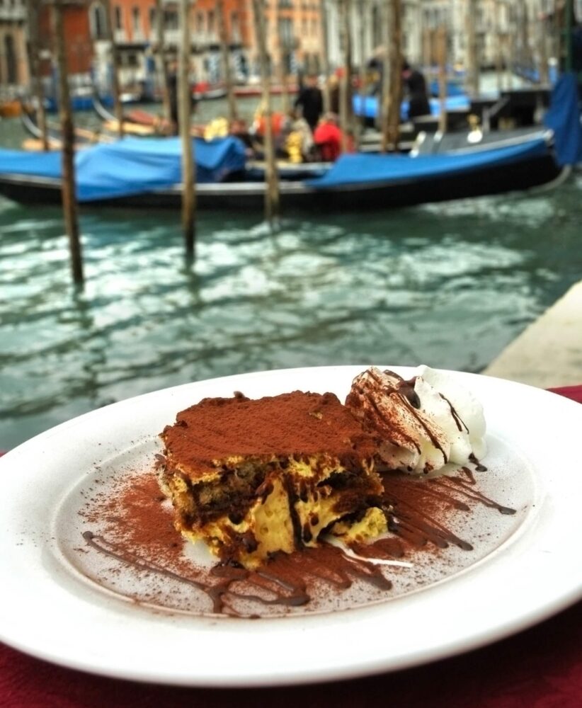 Tiramisu and cream shown with a venice gondola background