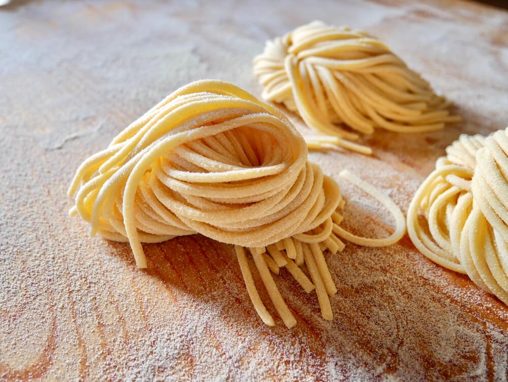 handmade bigoli pasta strands on a floury work surface