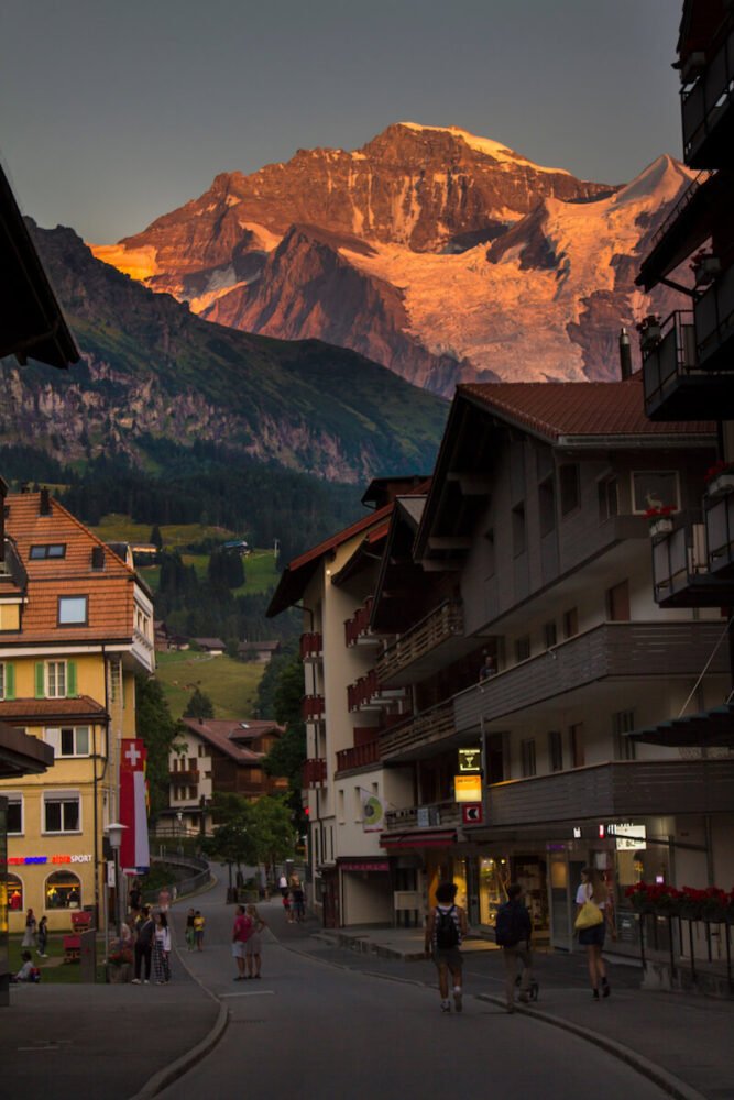 Sunset in the swiss town of Wengen with people walking around the pain street in town in summer