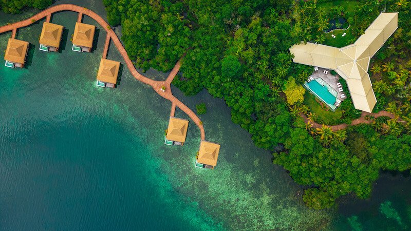 View of the gorgeous landscape of Nayara bocas del toro from the air with glimpse of pool and six bungalows floating over the sea