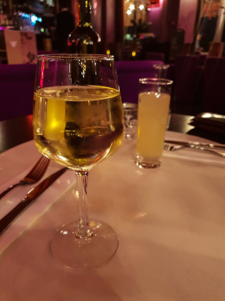 Typical french aperitif: glass of french white wine and a glass of Ricard on the background, in a romantic atmosphere during a dinner for two in a bistro