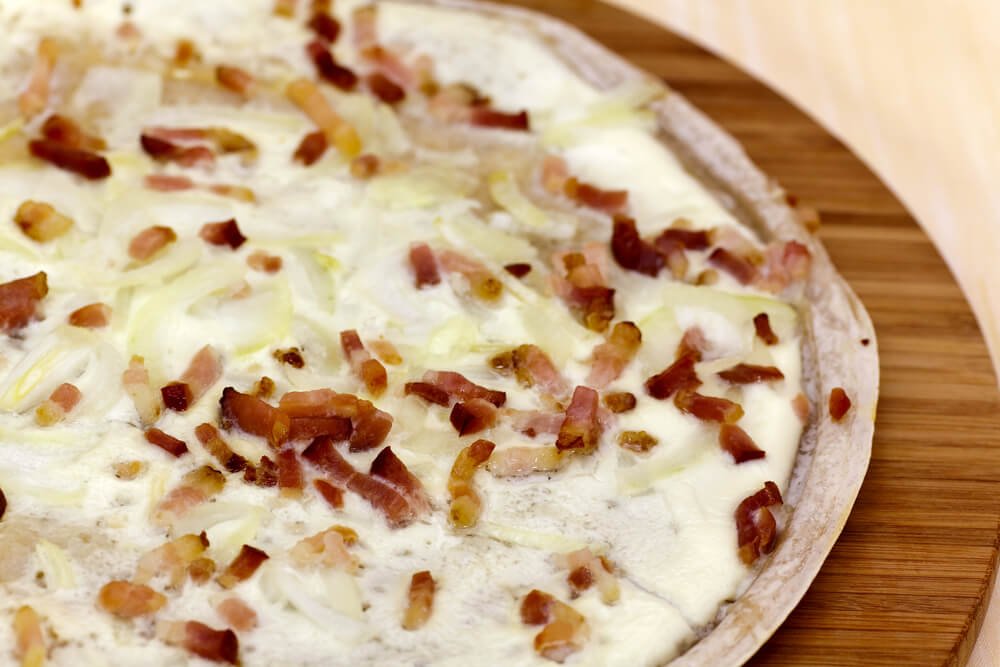 a pizza with cheese and pieces of bacon