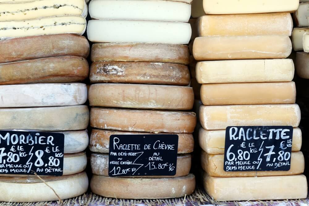 a selection of french cheeses with handwritten signs on chalkboards