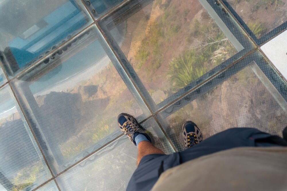 person stepping on the skywalk at cabo girao looking over the atlantic ocean below them