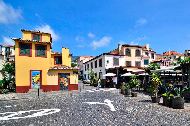 the downtown of funchal with road signs painted on the road ground indicating one-way and no-traffic spots