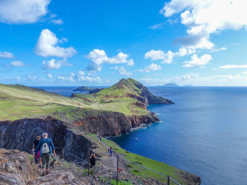 Landscape and Rock formations at the coast of Ponta de São Lourenço, with people walking along the path as well, on a sunny day