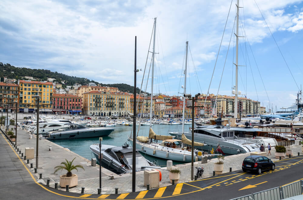 the port area or marina of nice with brilliant colored building sin the background and hill