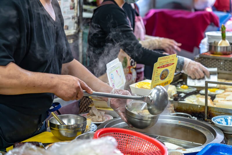 Local turnip cake vendor in Taichung Second Public Market, man pouring soup into a hot bowl.