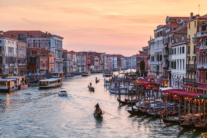 view of venice at night with gondolas going past into the sunset