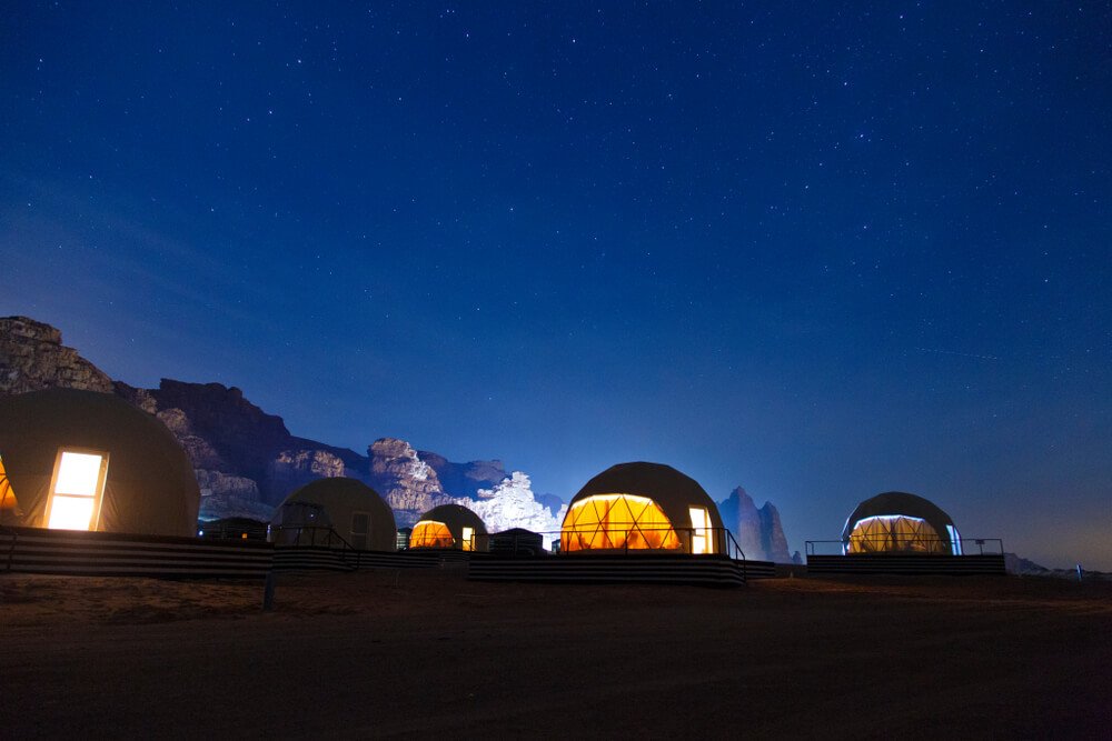 wadi rum bubble hotel at night with everything lit up and night sky