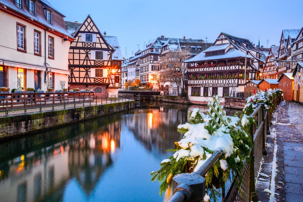 the winter scenery of france strasbourg canal with some snow on the winter decorations and half-timbered houses along a canal at blue hour just after sunset