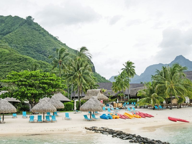 kayaks for rent on the shore of the hilton moorea lagoon resort with backdrop of mountains