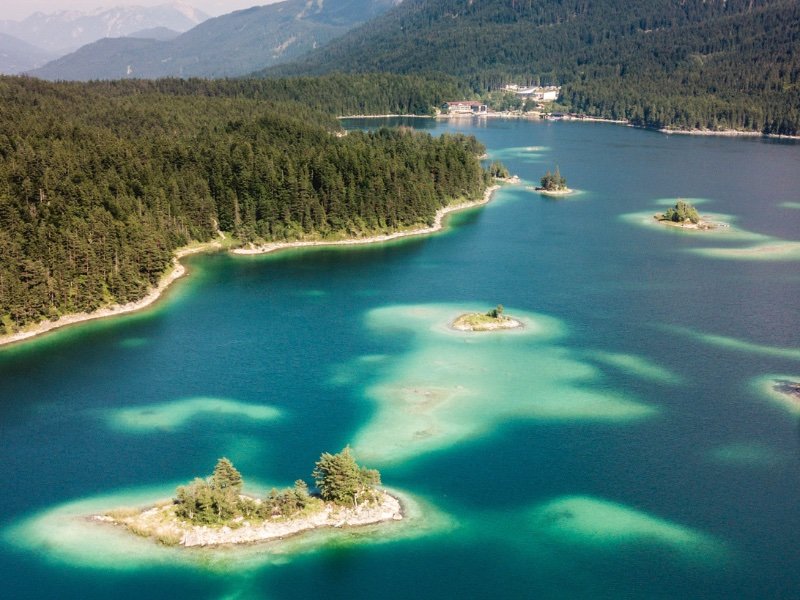 the beauty of lake eibsee as seen from a higher viewpoint with small "islands" in the lake with paler colors of water around the islands