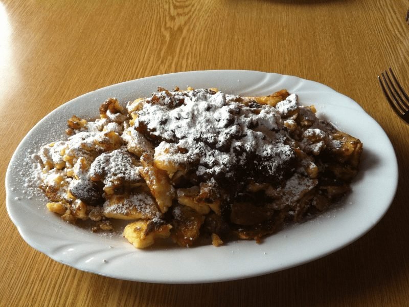 the famous Kaiserschmarrn scrambled pancake with jam and powdered sugar at a restaurant with a fork 