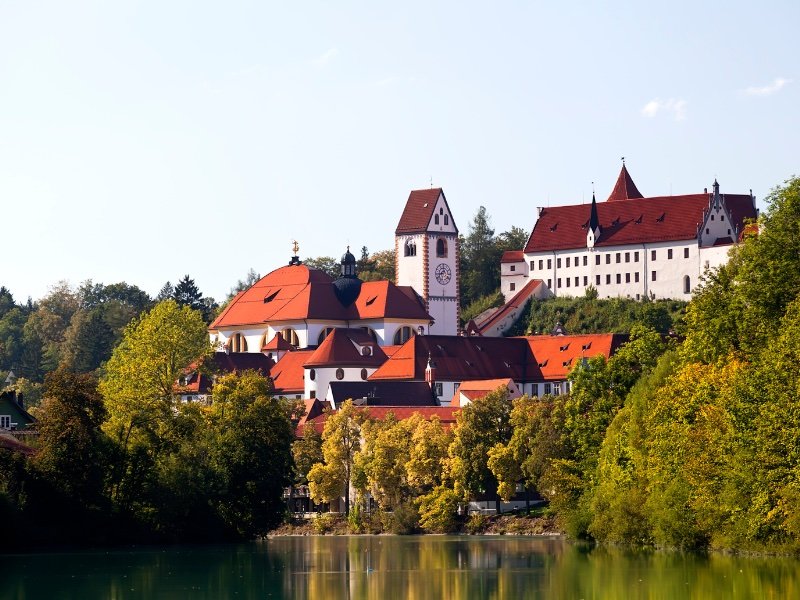 view of the castle above the town of fussen, as seen from a river side, on a sunny day