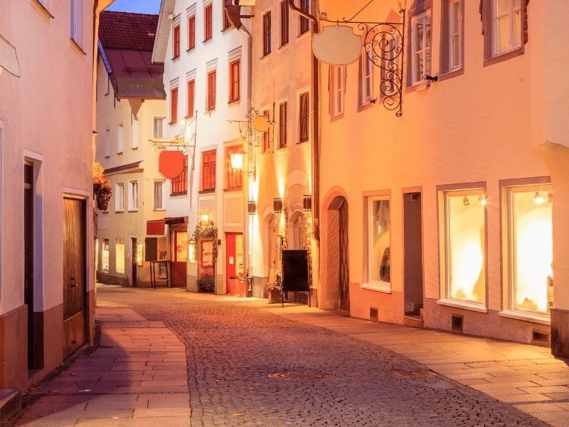 a view of an old town street in fussen at night with lamplight and pastel walls