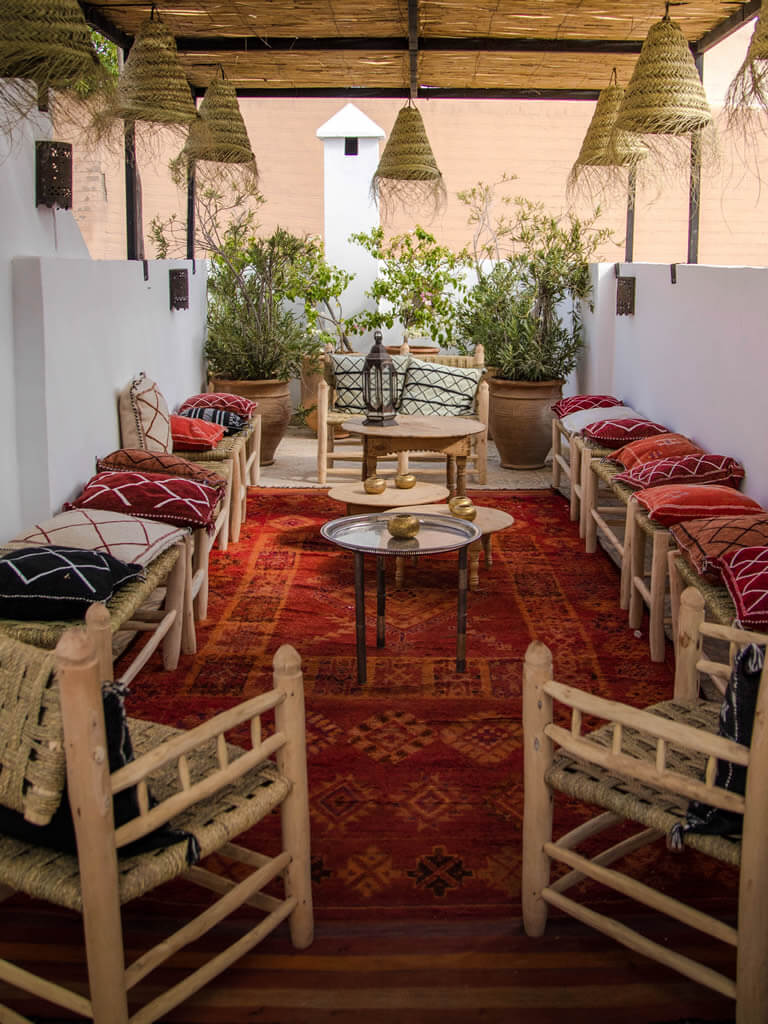 interior of a marrakech riad in red carpet, wooden chairs, etc.