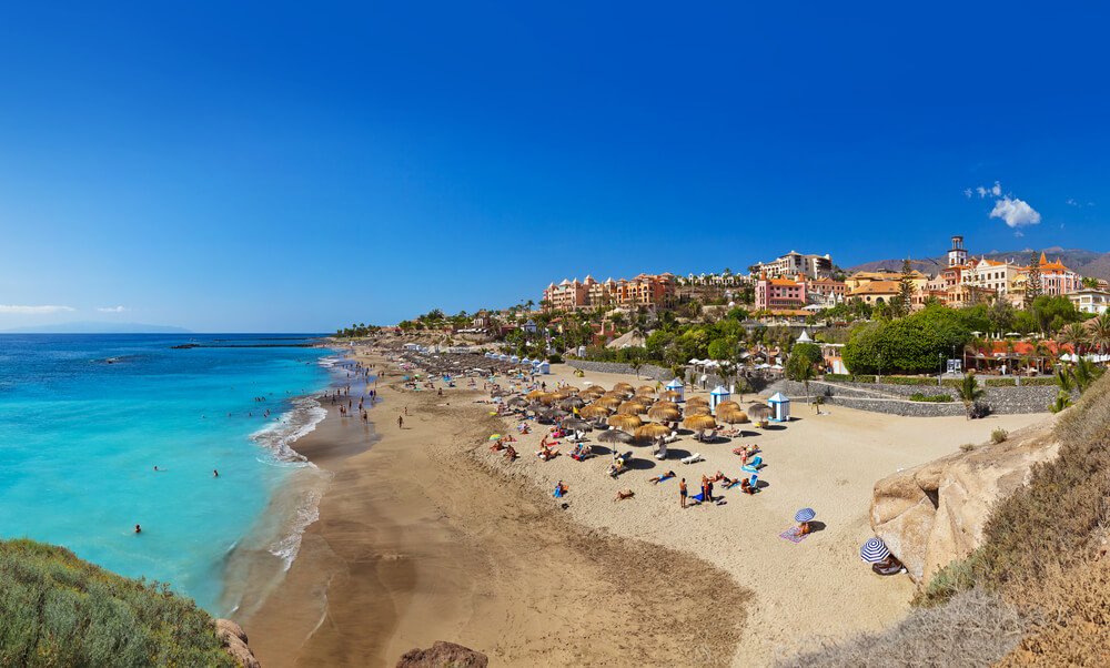 Beach Las Americas in Tenerife island - Canary islands of spain, on a sunny day with a turquoise blue sea and umbrellas on the coast