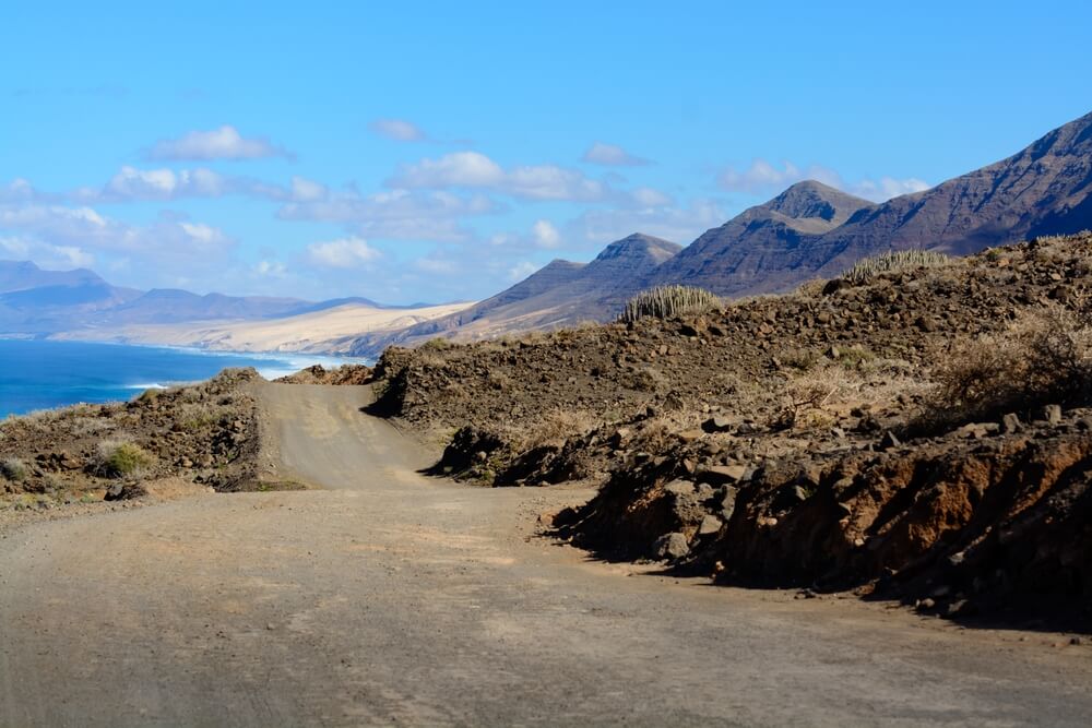 View on difficult to access golden sandy long Cofete beach hidden behind mountain range on Fuerteventura, Canary islands, Spain