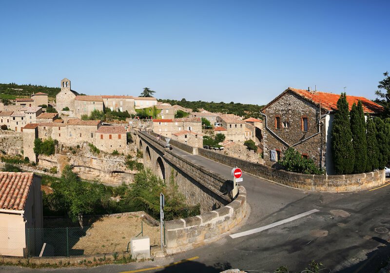 view in a provence town with a road that is mostly empty and a small town