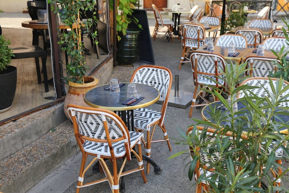 Arles city, France. Outdoor cafe tables in Arles. with traditional black and white chairs and round tables.