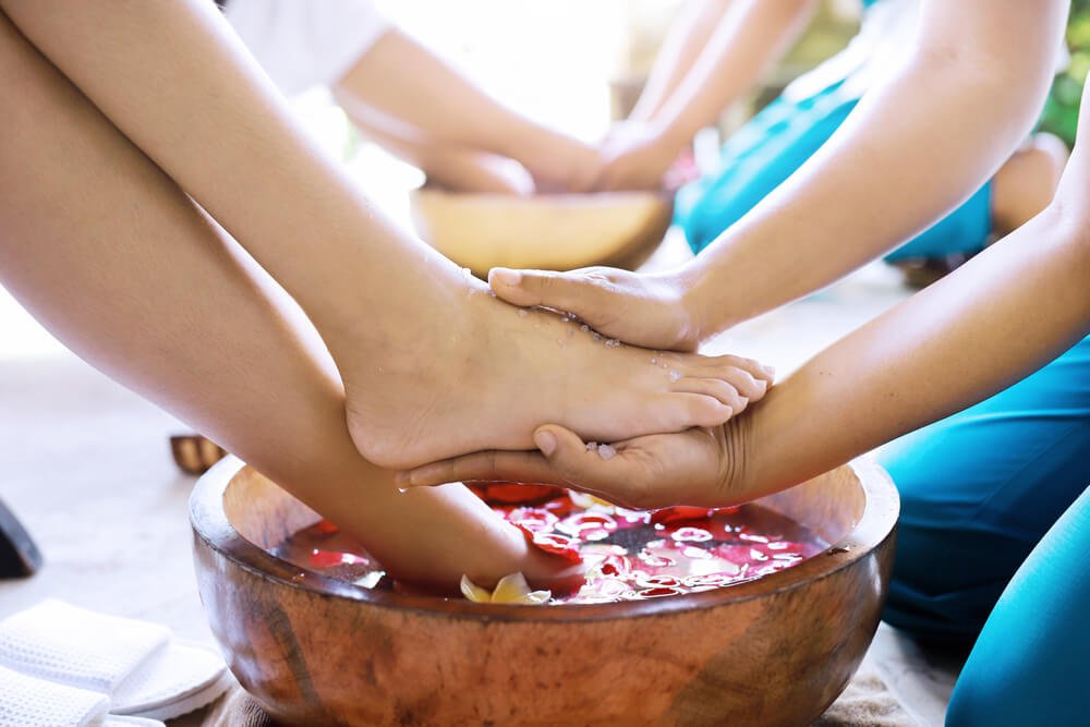 a foot bath and foot massage in a bath with flowers in bali