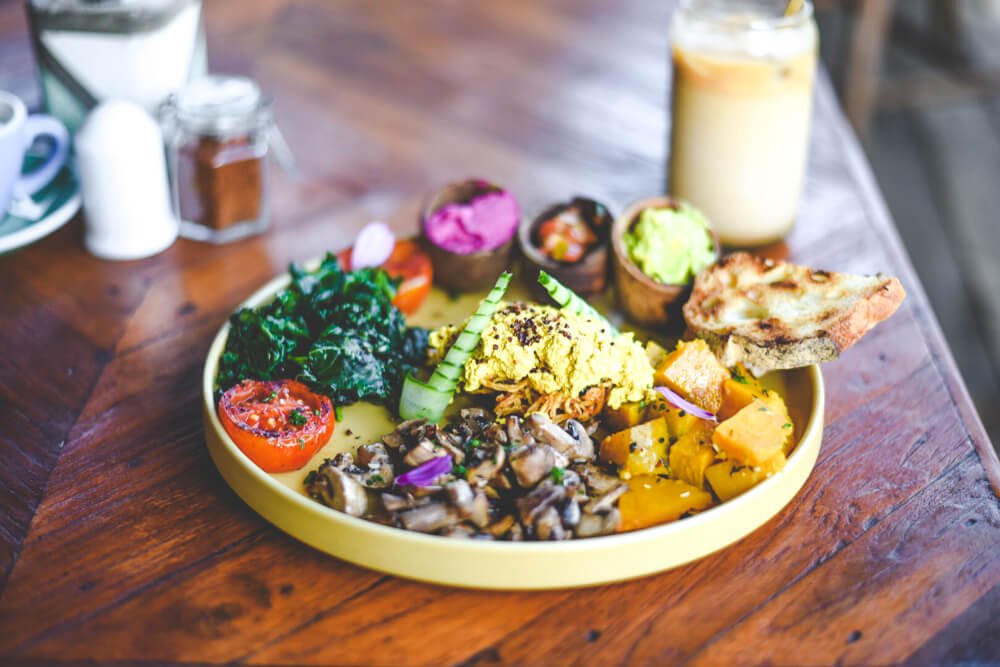 vegan tofu scramble with lots of fresh food like guacamole, sweet potato, mushroom, hummus