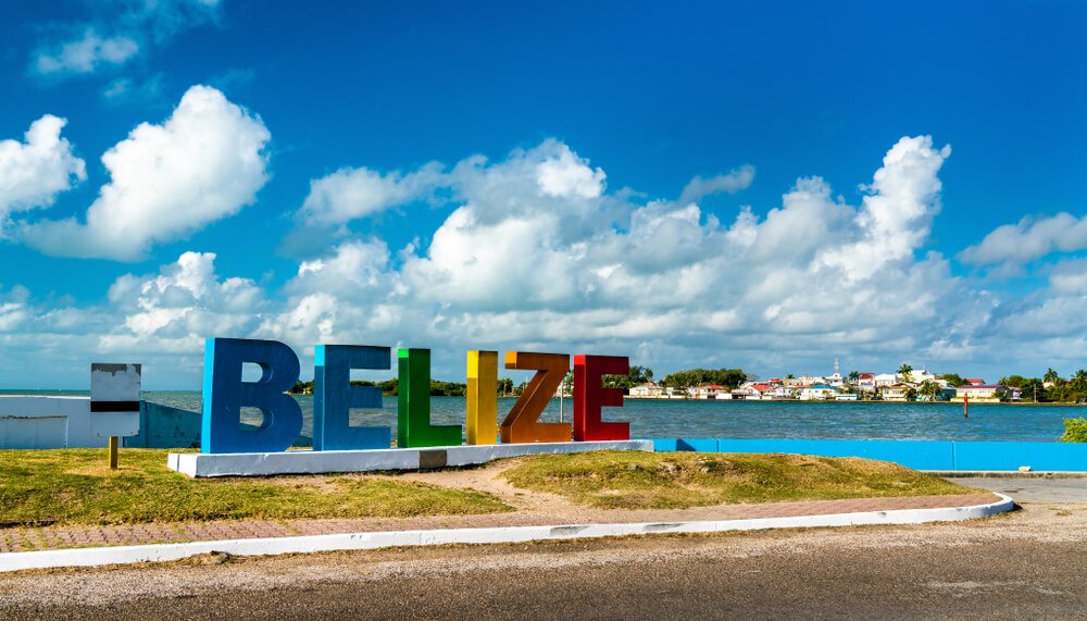 the sign for belize city on the water with houses in the distance