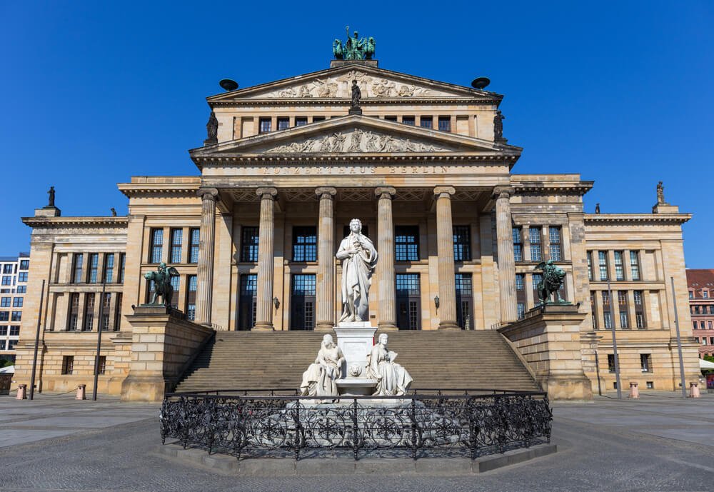 The concert hall in the Mitte section of berlin in the heart of the city center, a perfect place to start a Berlin itinerary, with a statue and steps and pillars in front of the entrance facade