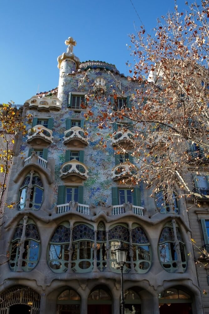 Casa Batlló whimsical architecture on a sunny day with no clouds in the sky in late afternoon with mosaic walls