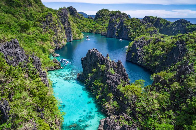 The El Nido part of Palawan, Philippines with an aerial view of beautiful turquoise lagoon and limestone cliffs covered in greenery.
