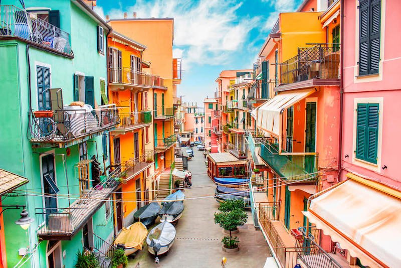 Traditional typical Italian village of Manarola with its colorful houses, fishing village style, fishing boats, and blue sky.