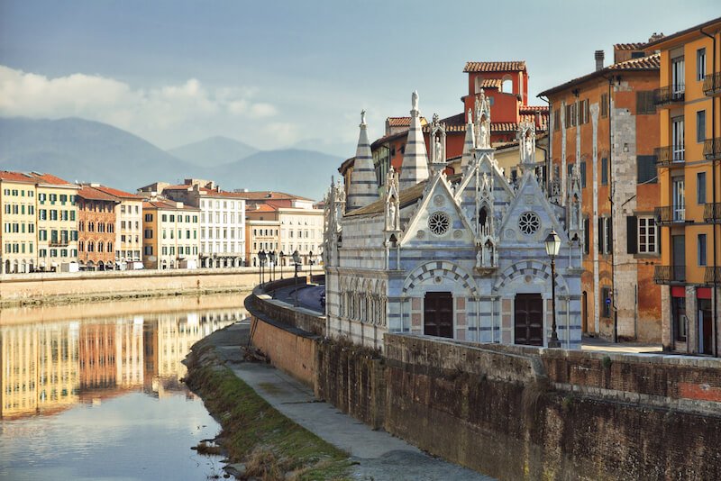 On the bank of the Arno River, the striped facade of the marble-faced Gothic church Santa Maria della Spina in Pisa