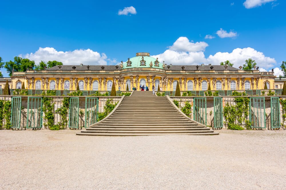 Sanssouci Park and its trademark yellow palace with green roof on a sunny day in Potsdam