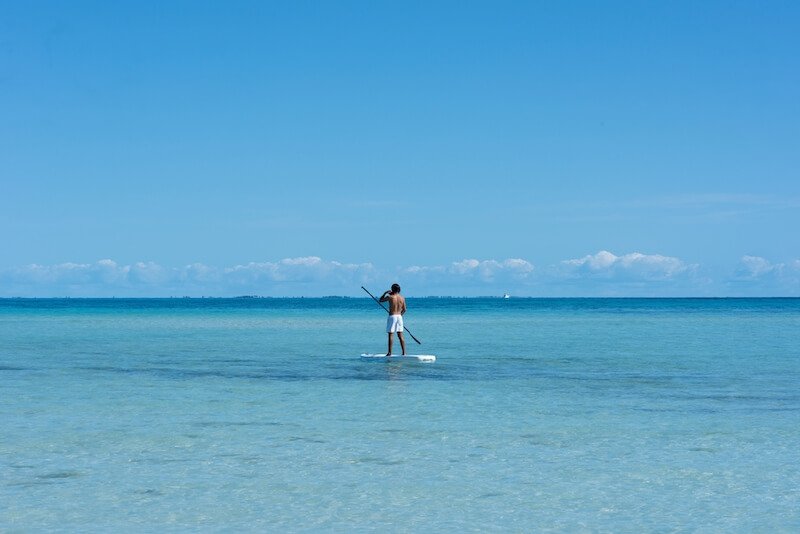 man in swim trunks on a stand up paddle board